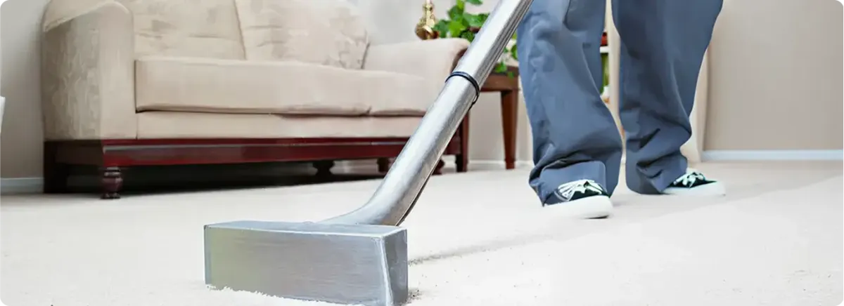 Carpet cleaning technician using a hot-water extraction wand on a light-colored carpet in a living room, Baton Rouge, LA.