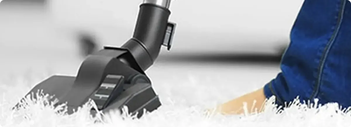 Close-up of a professional vacuuming a white carpet in Saint Gabriel.